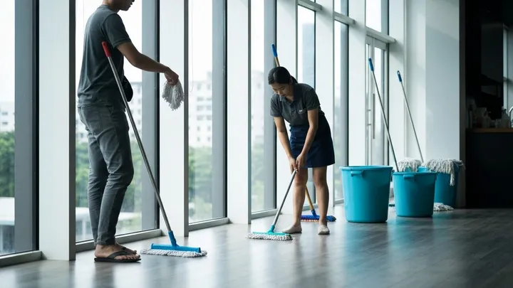 Two-person CLEANROVA crew mopping a large glass-walled Bangkok room after renovation